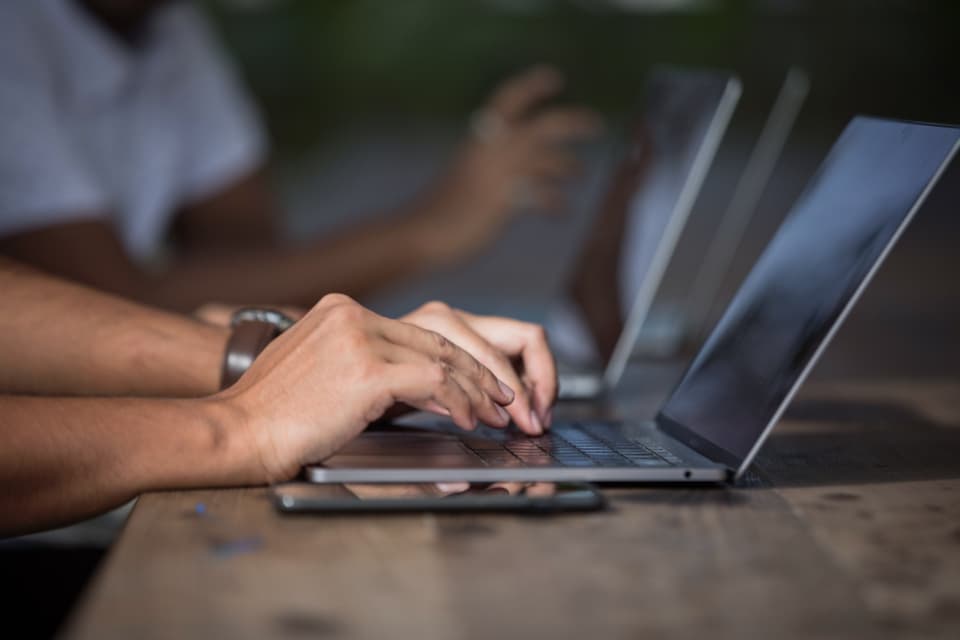 Hands building software on a laptop at a workbench