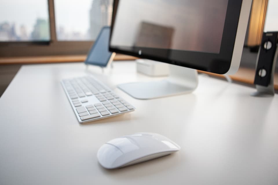 A quiet home-office desk and monitor by a window